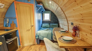 A compact, wooden interior with a kitchenette, a dining area, and a bed with a view. - Hobhole (Spilsby)