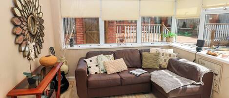 A cozy living room with a brown leather sofa, a decorative mirror, and a wooden side table.