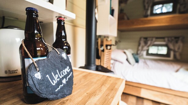Una mesa de madera con dos botellas de cerveza y un cartel de bienvenida.