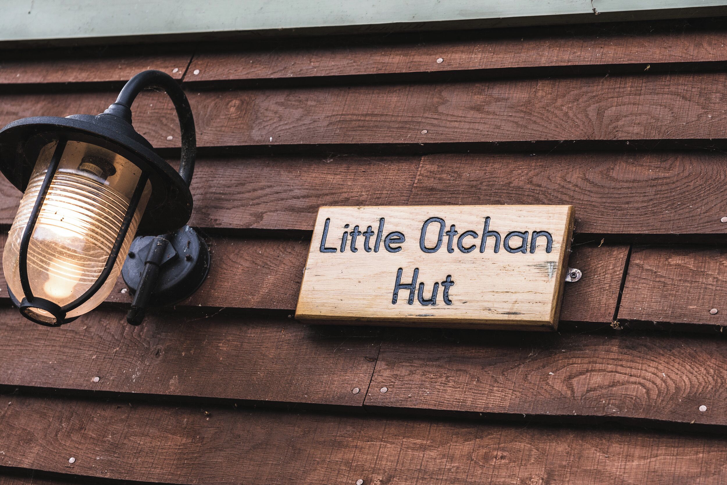 Puinen kyltti, jossa lukee ”Pienen Otchanin maja”, on kiinnitetty puiseen seinään.