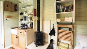 Una cocina acogedora con estufa de leña, armarios de madera y una estantería llena de libros.