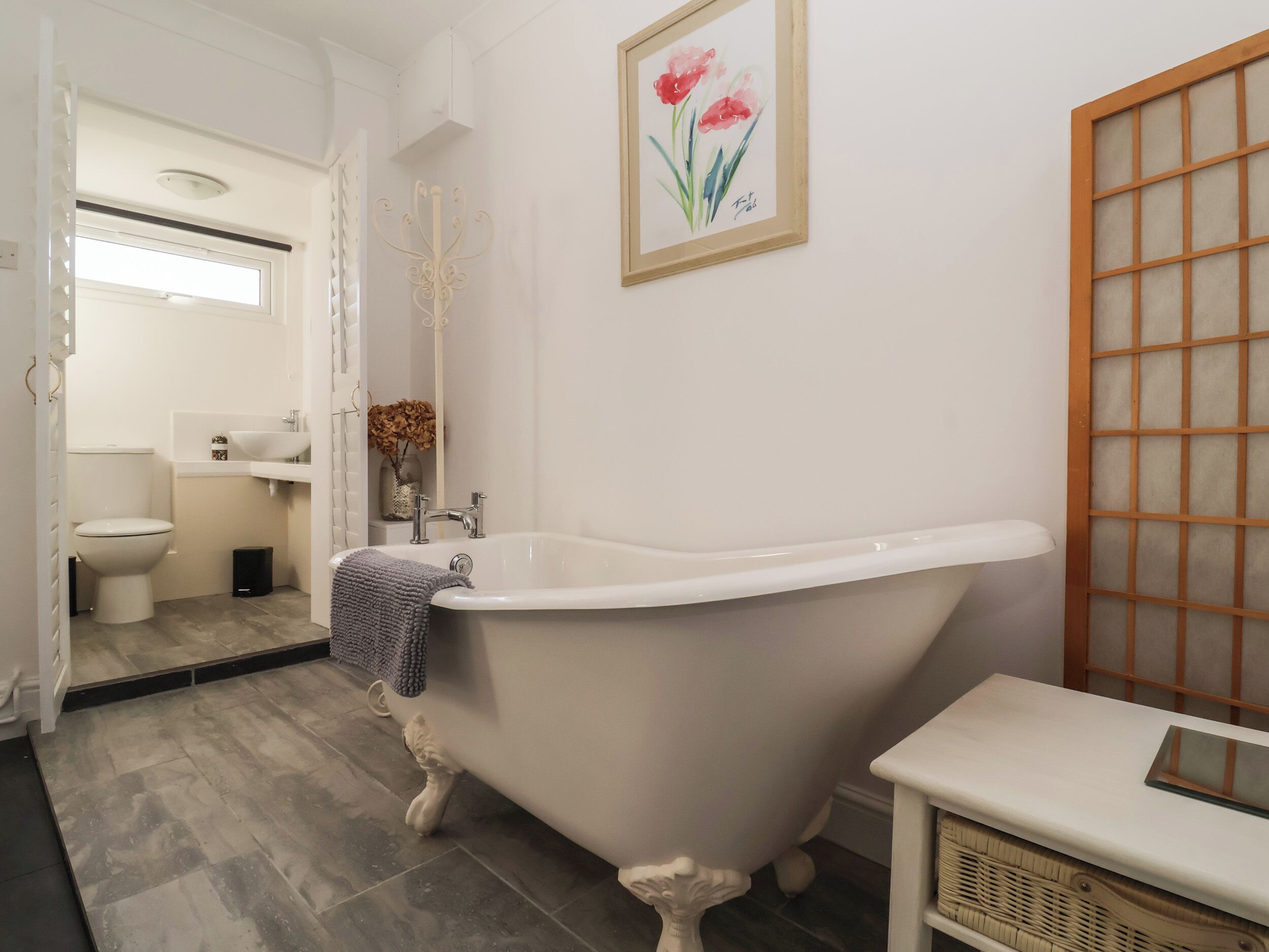 A bathroom with a freestanding bathtub, a toilet, a sink, and a mirror.