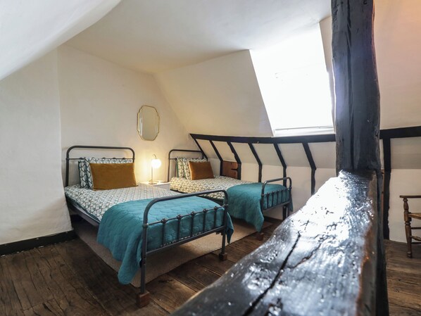 Une chambre avec deux lits, une petite table, un miroir et une fenêtre.