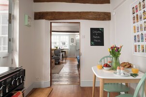 Una cocina con armarios de madera, estufa y comedor con mesa lista para el desayuno.