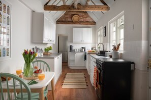 A kitchen with white cabinets, a black refrigerator, and a wooden ceiling. - Hudson House (Milton Keynes)
