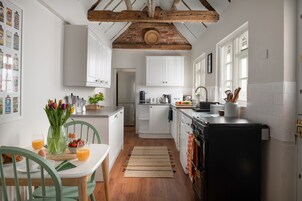 Una cocina con armarios blancos, un refrigerador negro y techo de madera.