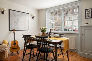 Un comedor con una mesa preparada para cuatro personas, una guitarra y un mapa en la pared.