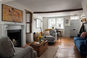 Una sala de estar con chimenea, un sofá azul, un sillón gris y una mesa de centro de madera.
