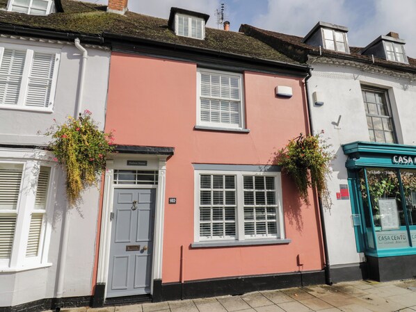A building with a pink facade, white shutters, and a door labeled "Hudson House." - Hudson House (Milton Keynes)