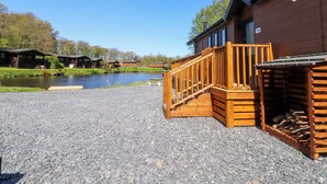 A wooden building with a gravel driveway and a wooden staircase leading to a deck.