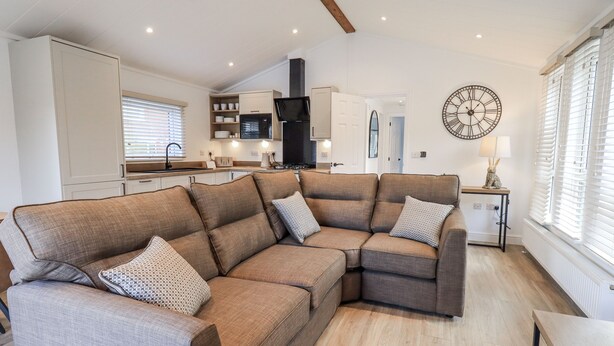 A modern living room with a sectional sofa, a small table, and a kitchen area in the background.
