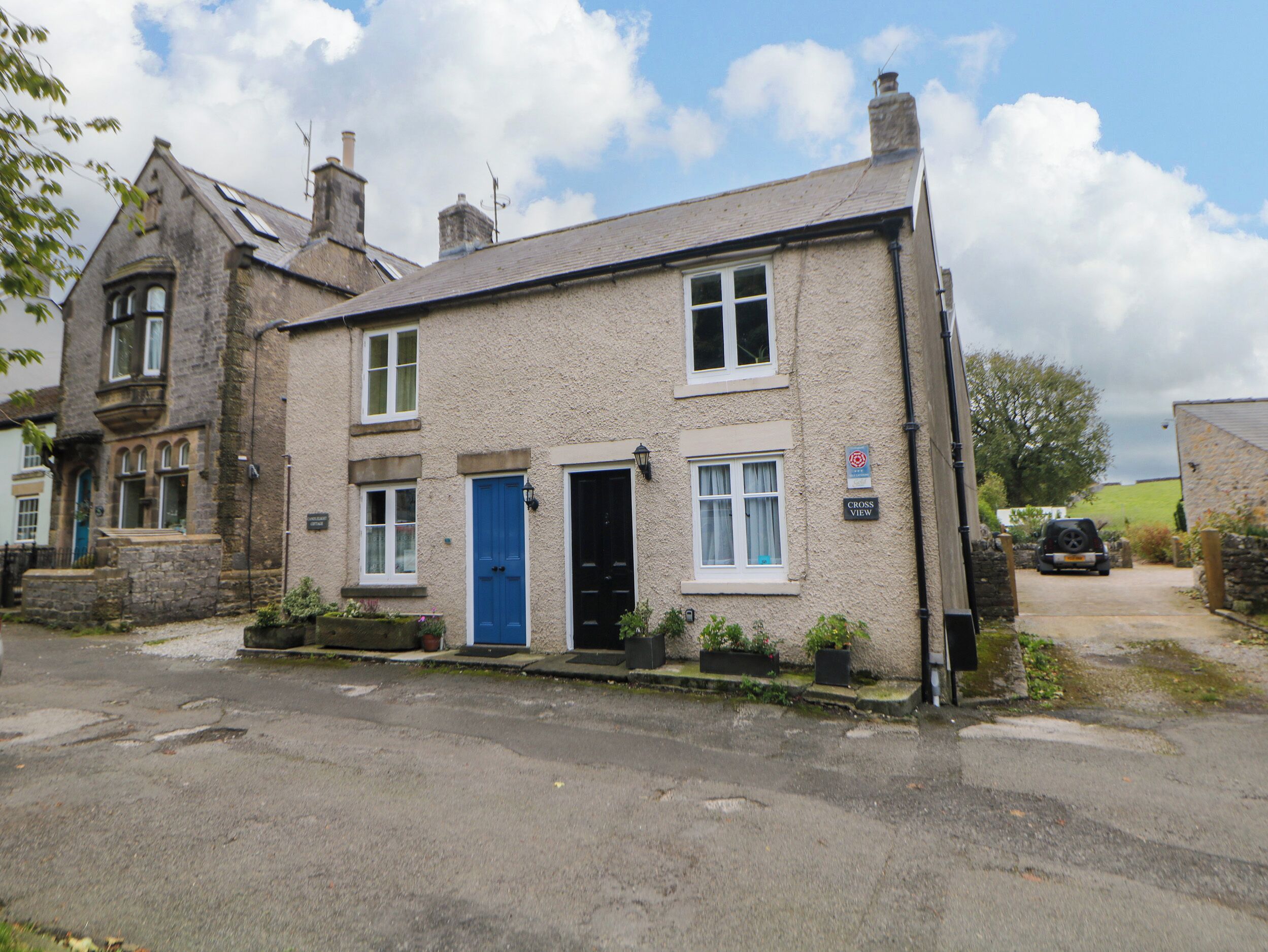 A two-story house with a blue door, a visible chimney, and a sign indicating a 'Cross View' location.