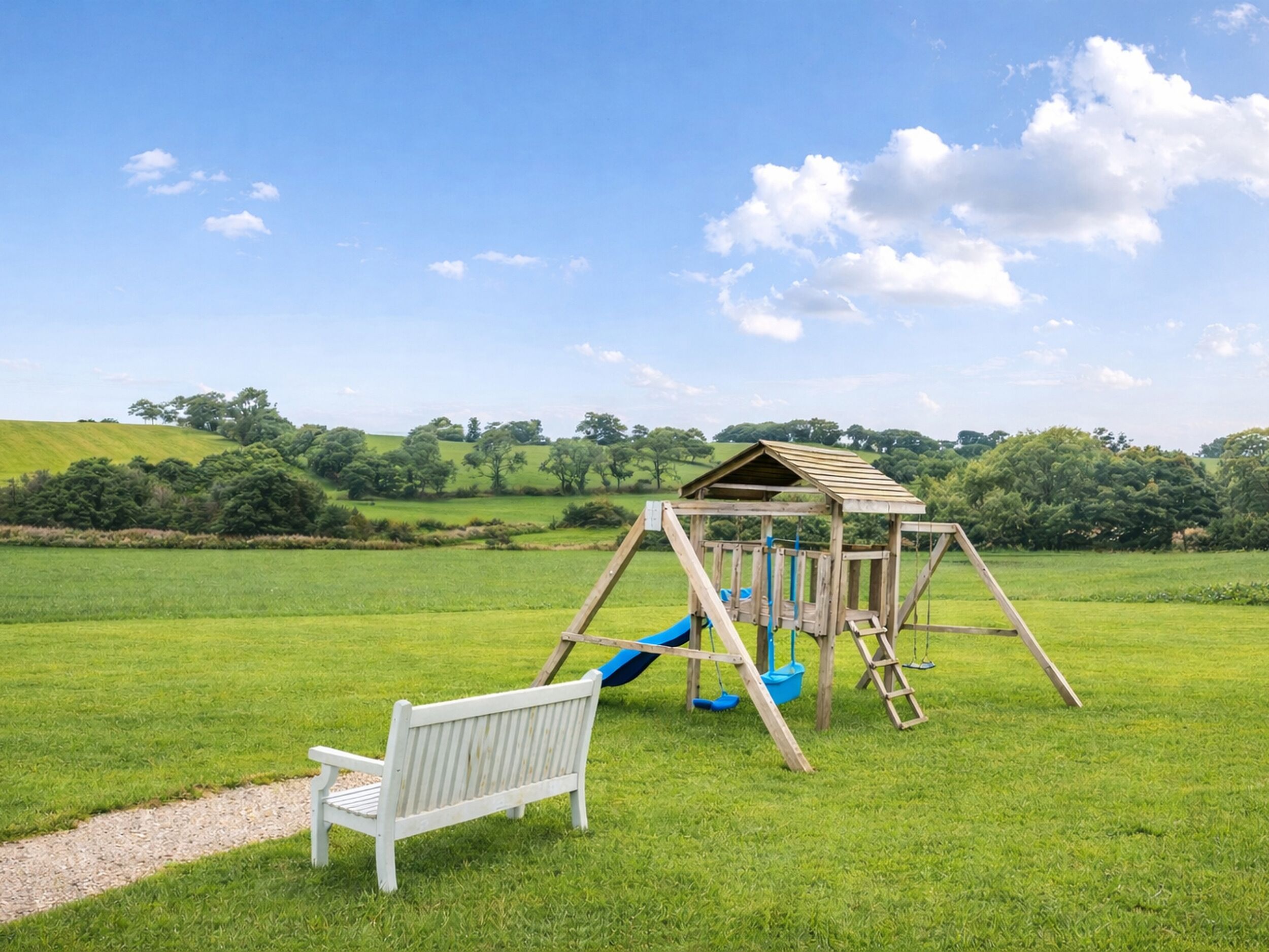 A wooden swing set with a slide in a grassy field.
