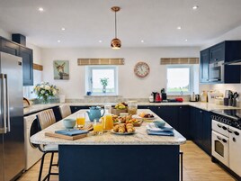 A modern kitchen with a central island, built-in appliances, and a large window providing natural light.