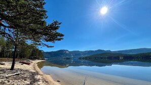 A beach with a clear view of a lake and mountains in the background.