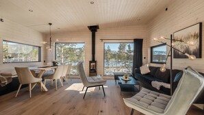 A modern interior with wooden walls, a dining area with chairs, a sofa, and a fireplace.