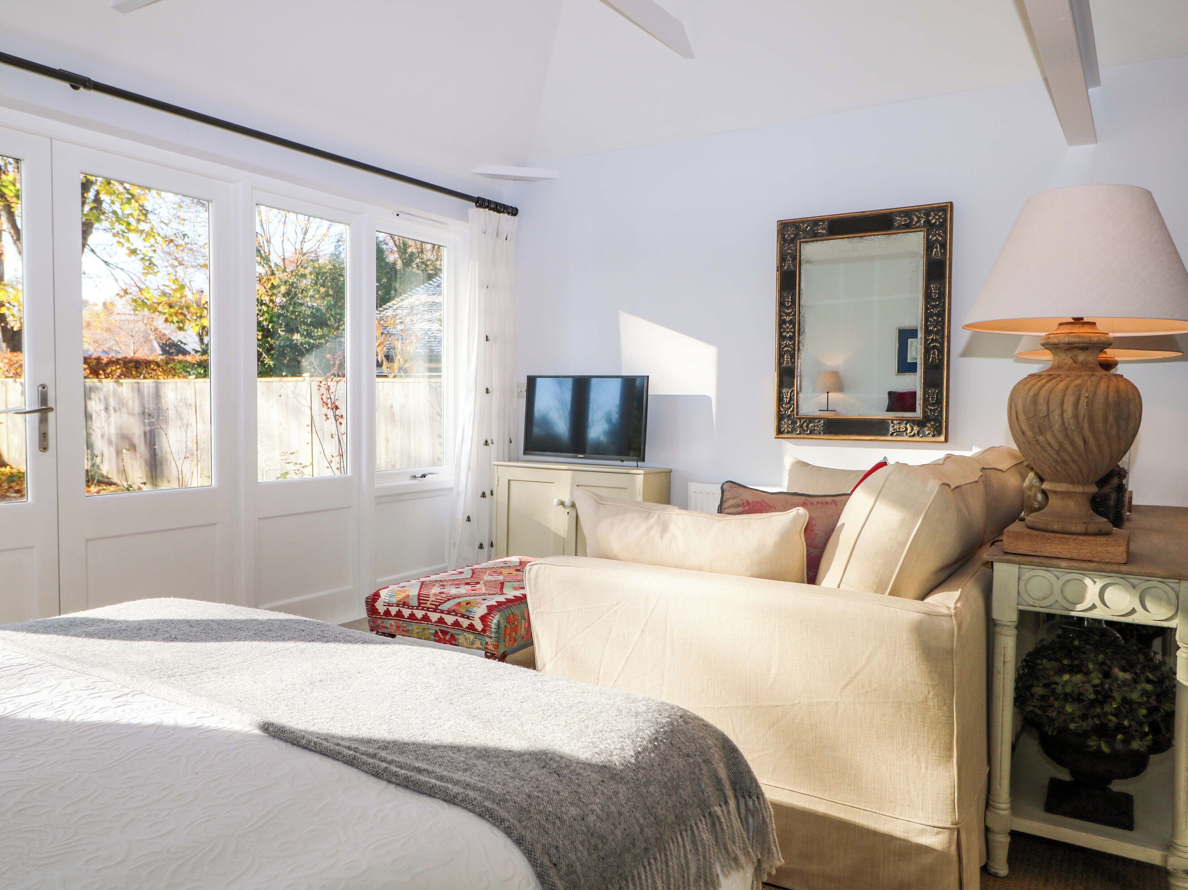 A bedroom with a bed, a TV, a lamp, and a mirror.
