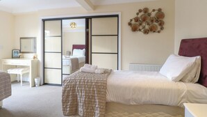 Ein Hotelzimmer mit einem Bett, einem Schreibtisch, einem Stuhl, einem Spiegel und einem Wandbild.