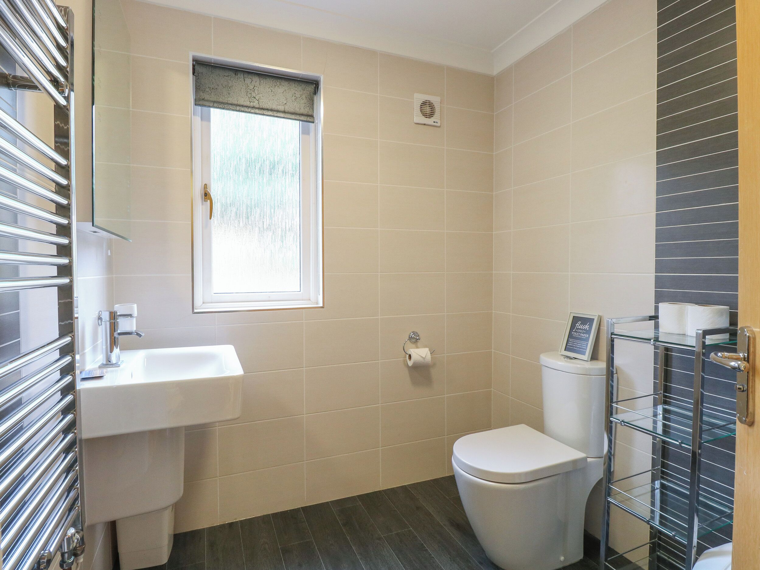 Een moderne badkamer met een wit wastafel, toilet en een raam met uitzicht.