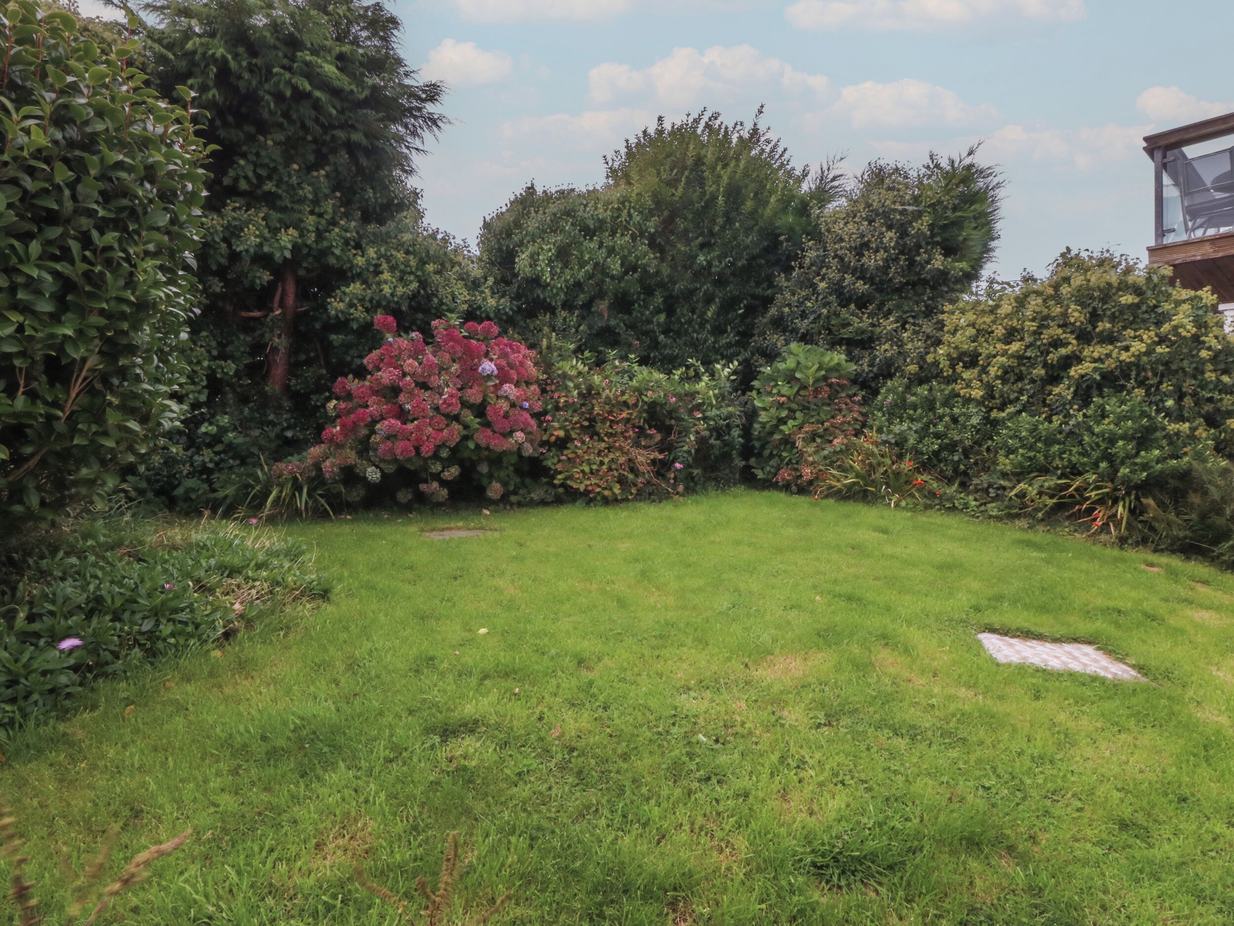 A well-maintained garden with a variety of shrubs and a lawn.
