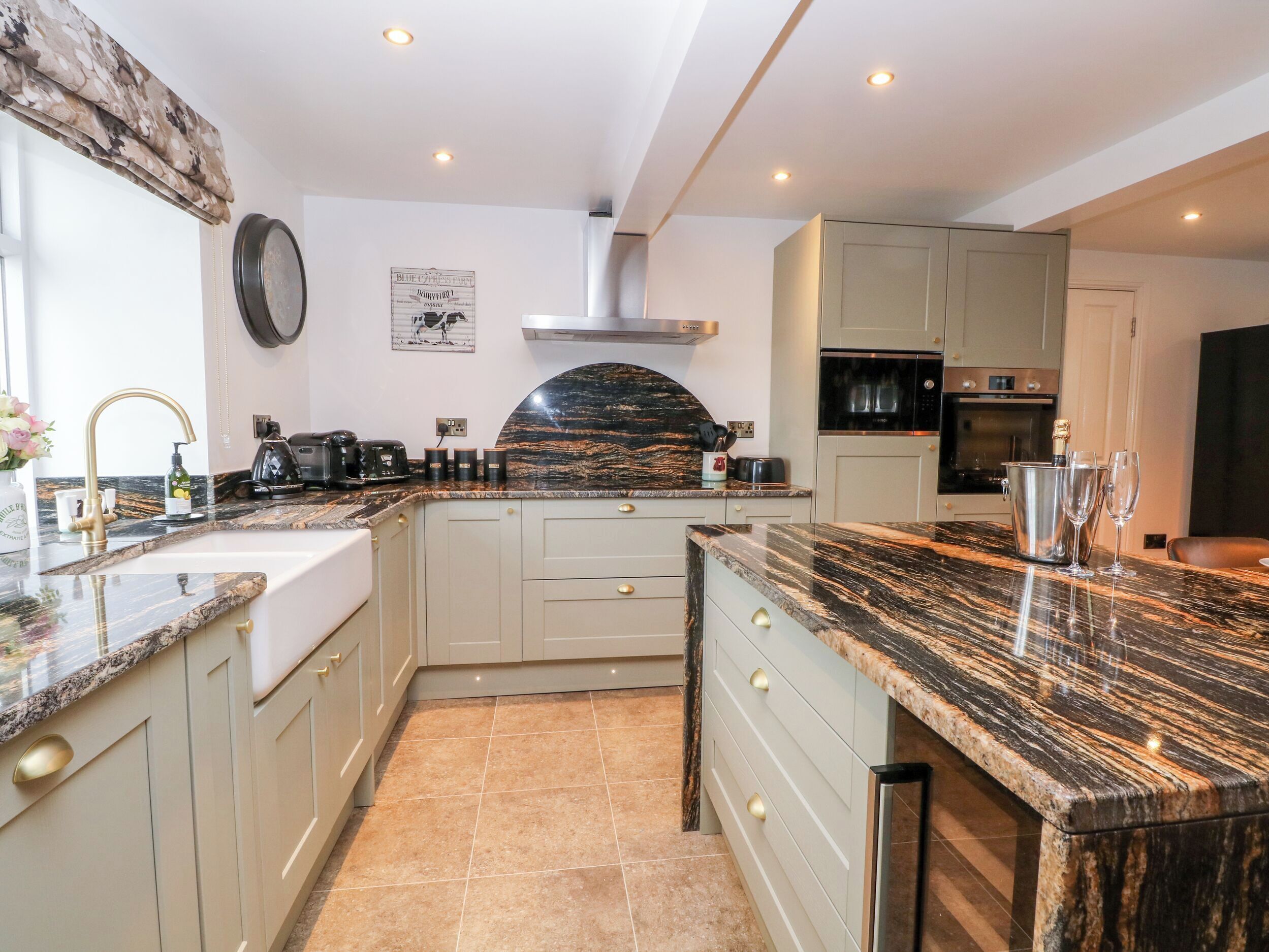 A modern kitchen with a marble countertop, stainless steel appliances, and a built-in oven.