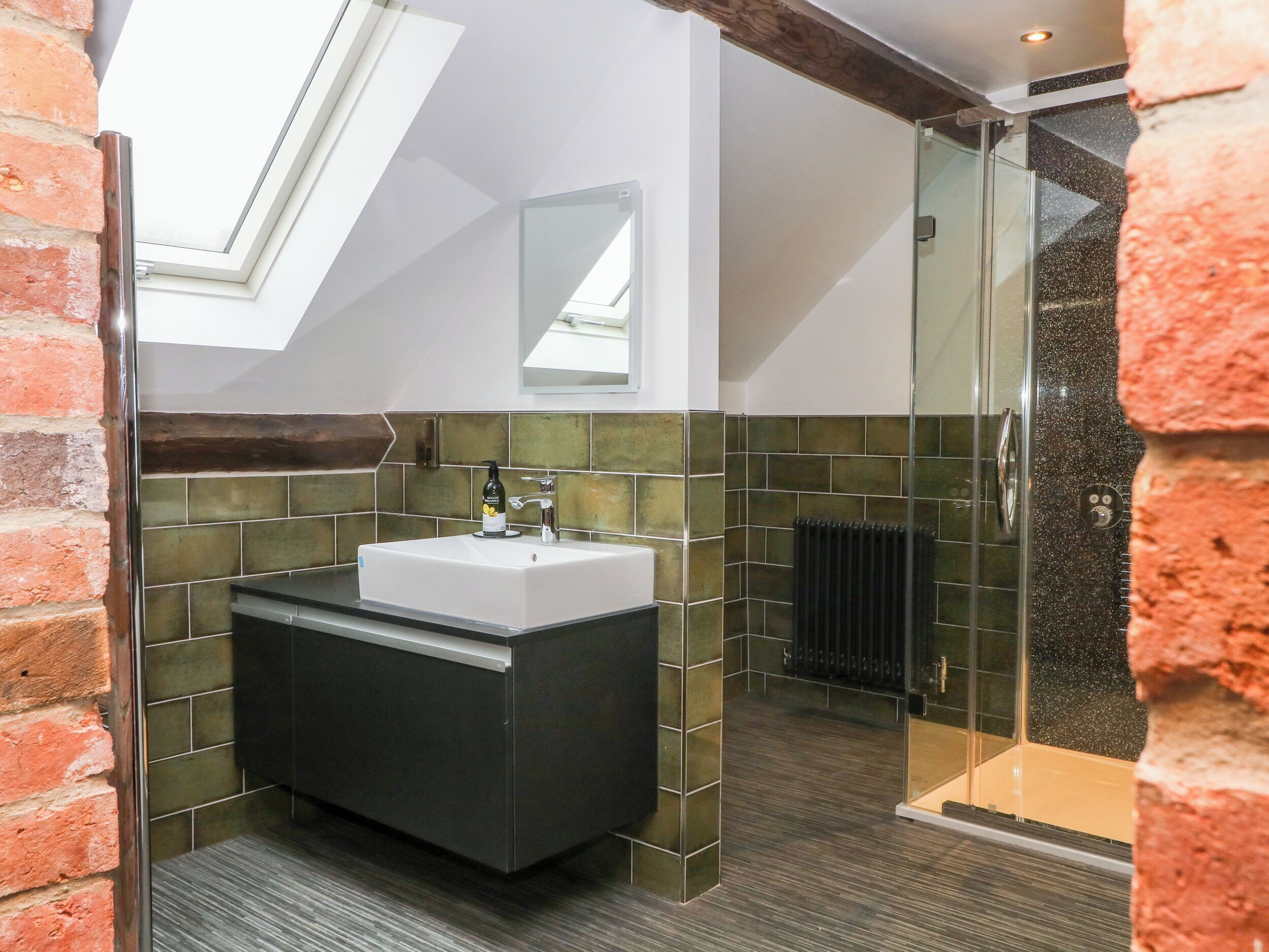 Un bagno moderno con finestra a lucernario, un lavandino spazioso e box doccia in vetro.