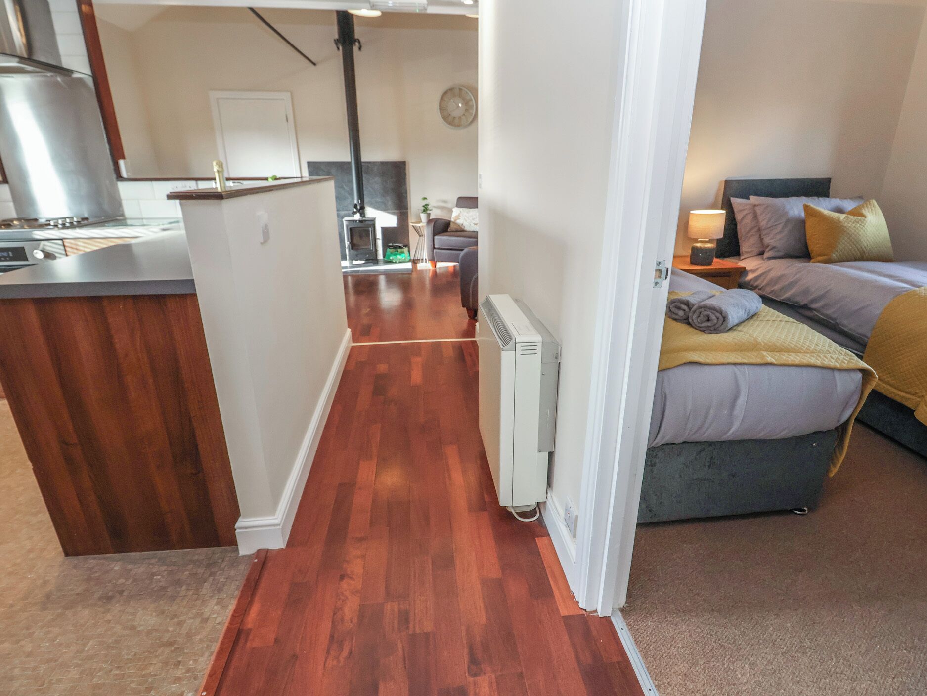 A compact living space with a kitchenette, a bed with a yellow blanket, and a small seating area.
