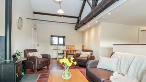 Uma sala de estar moderna com lareira, sofás de couro, uma mesa de centro de madeira e um espaço de jantar com janela.