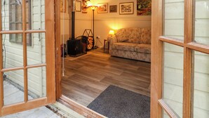 A cozy living room with a fireplace, a sofa, and a lamp. - The Cabin at Little Timbers (Ringwood)