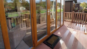 Una terraza de madera con puertas correderas de cristal que dan a un jardín trasero.