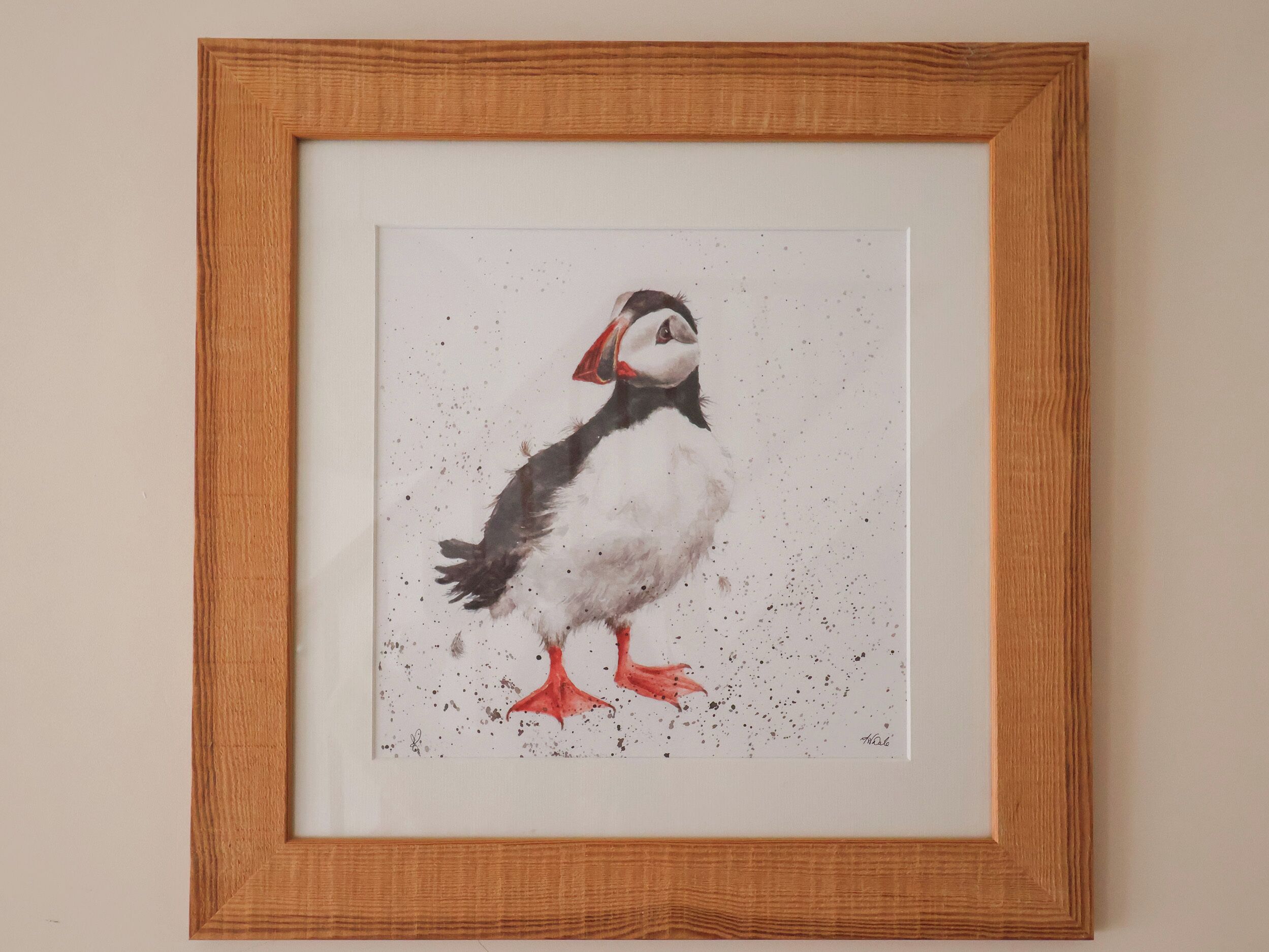 A framed artwork of a puffin on a plain background.