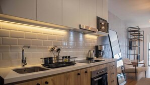 Una cocina moderna con azulejos tipo metro blancos, electrodomésticos de acero inoxidable y armarios de madera.