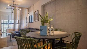 Una sala de reuniones moderna con una mesa redonda, sillas verdes, una planta en maceta y un cartel de bienvenida.