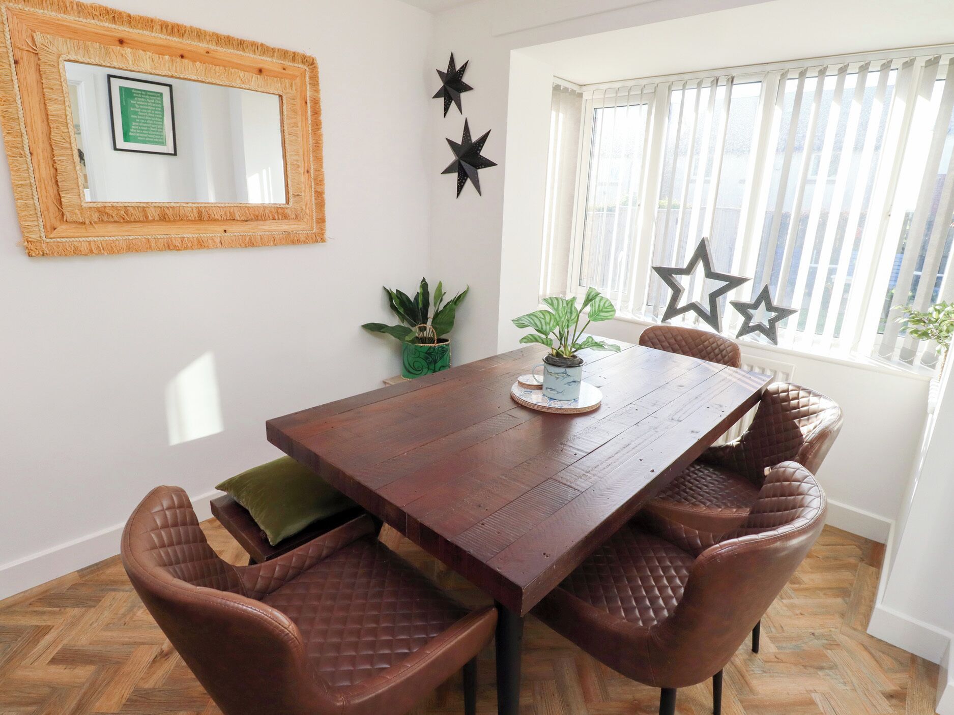 A dining area with a wooden table, leather chairs, a potted plant, and decorative stars on the wall.