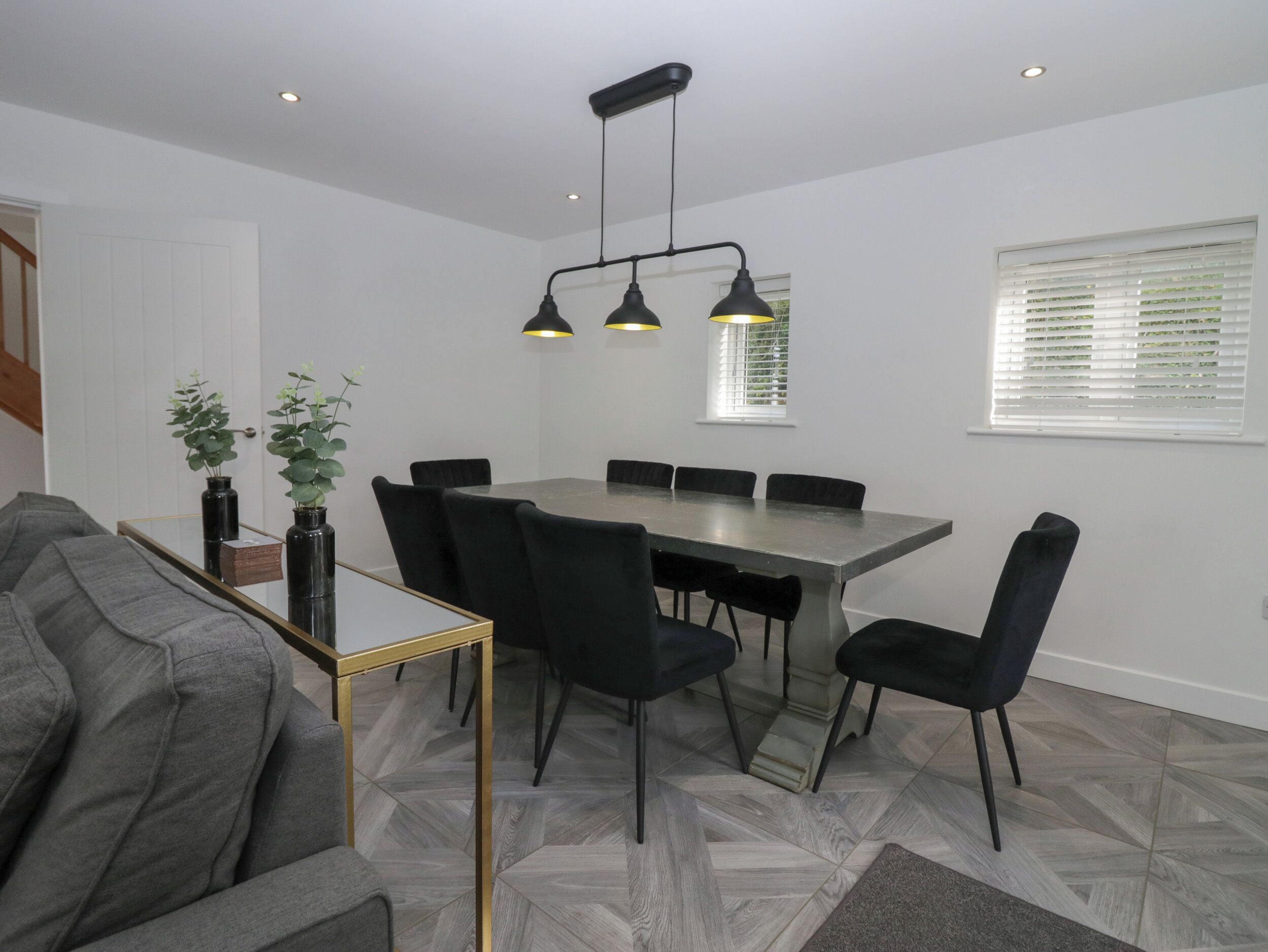 Een moderne eetruimte met een rechthoekige tafel, zwarte stoelen en hanglampen.