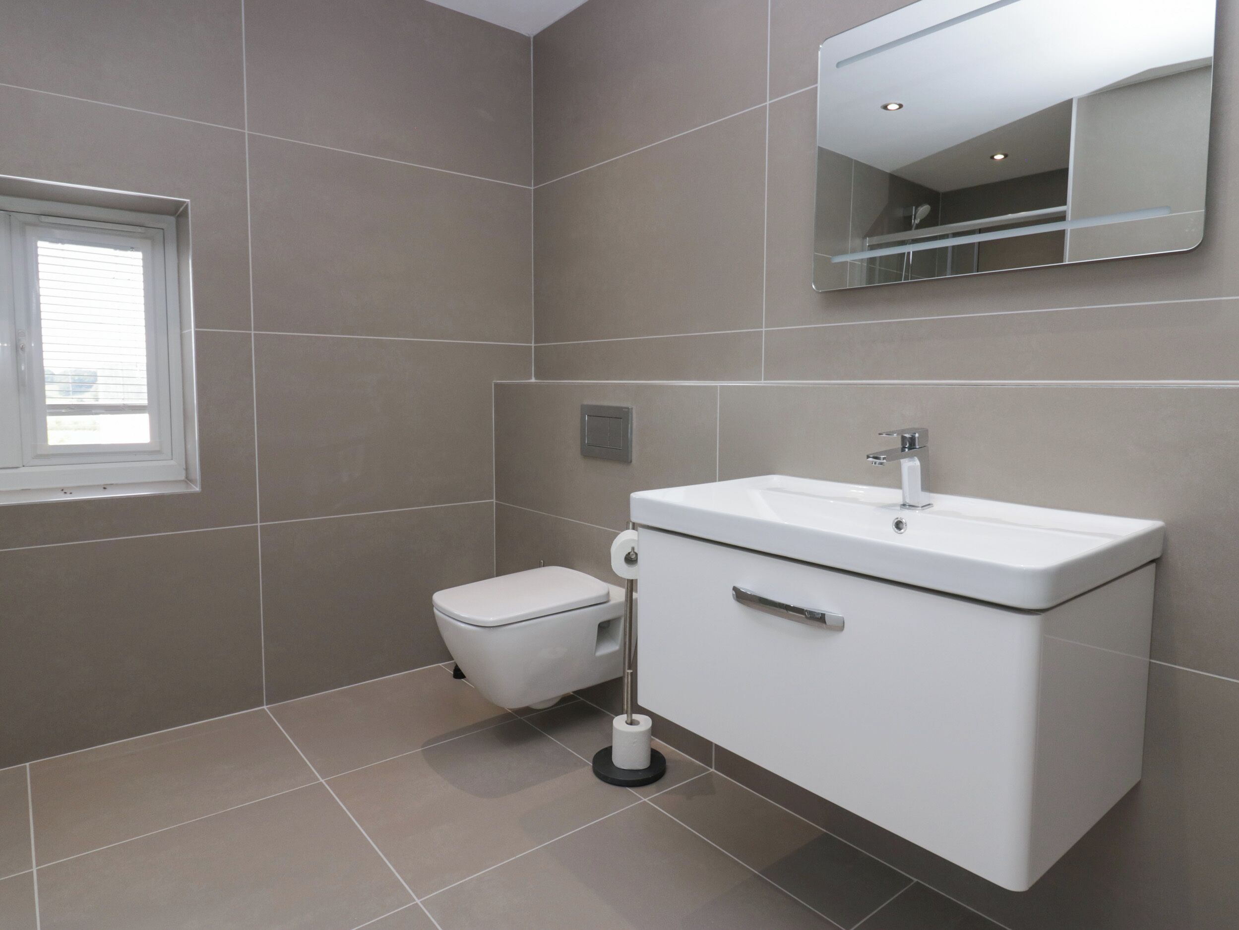 Un bagno moderno con il water, un lavandino e uno specchio.