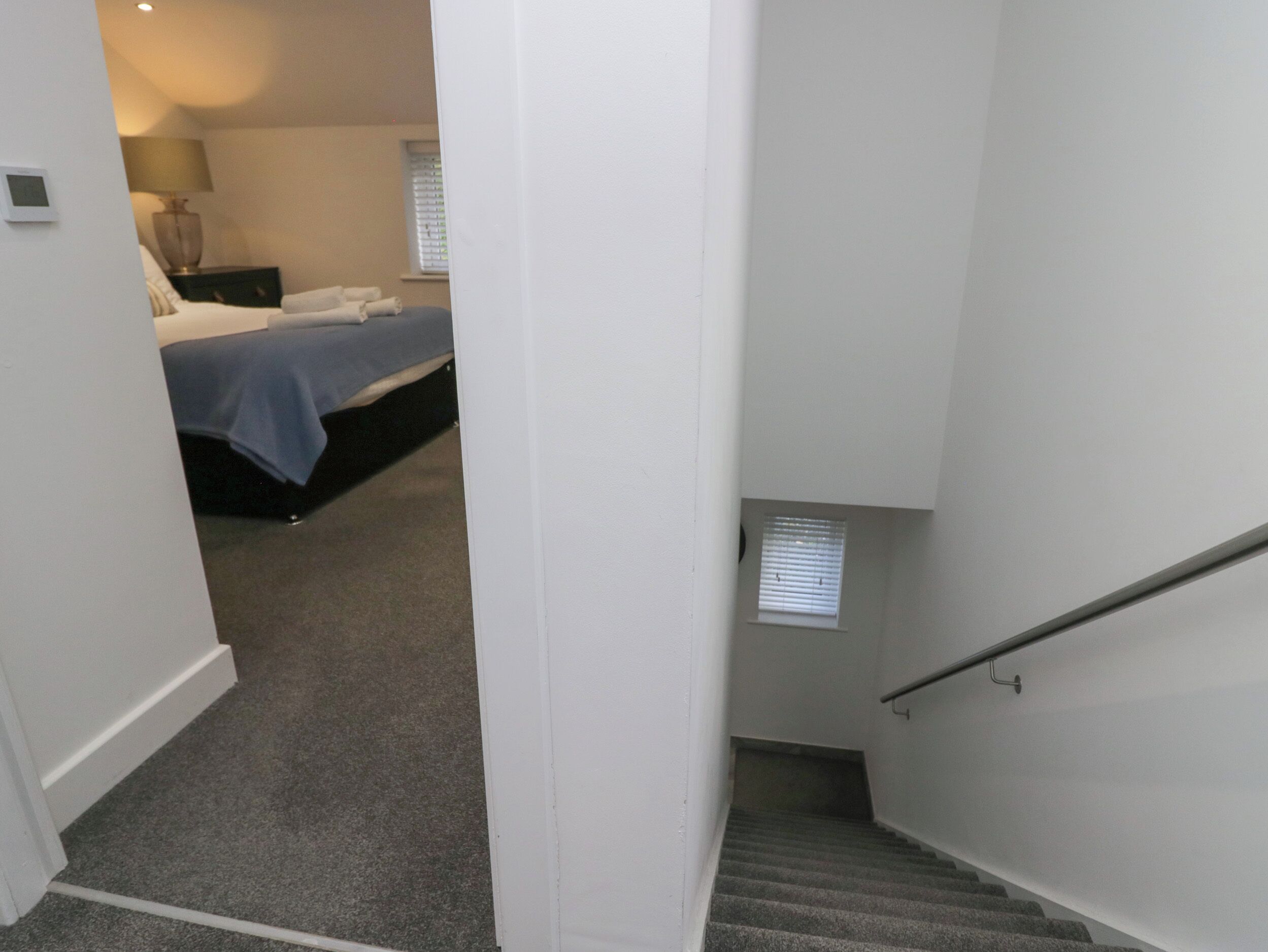 Eine enge Treppe führt zu einem Schlafzimmer mit einem Bett und einem Nachttisch.