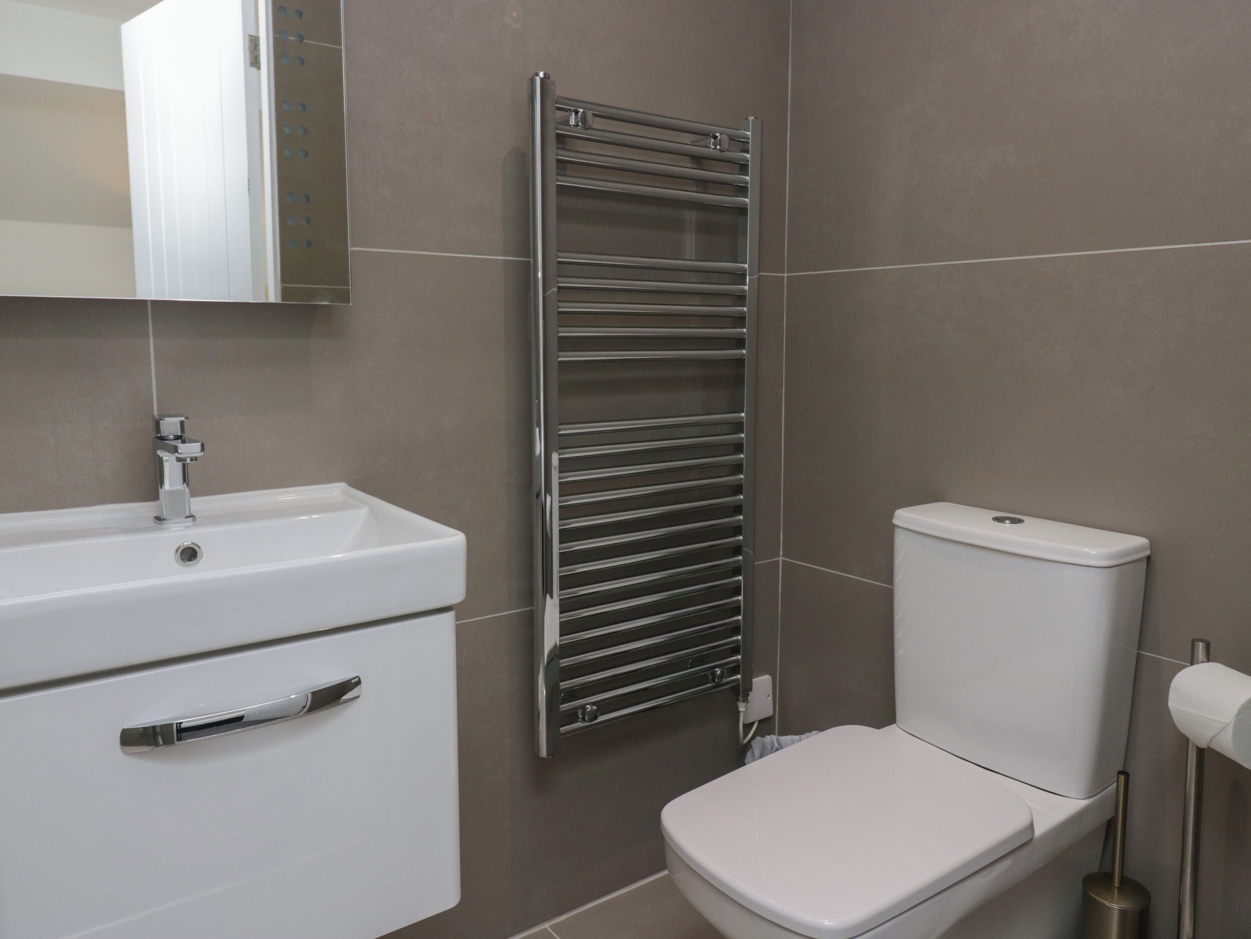 A bathroom with a white sink, a chrome towel rack, and a white toilet.
