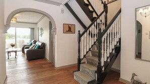 A staircase with black and white balusters, a wooden floor, and a framed picture on the wall. - White Gables (Norwich)
