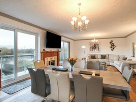 Una sala de estar moderna con comedor, ventanas amplias, chimenea y candelabro.
