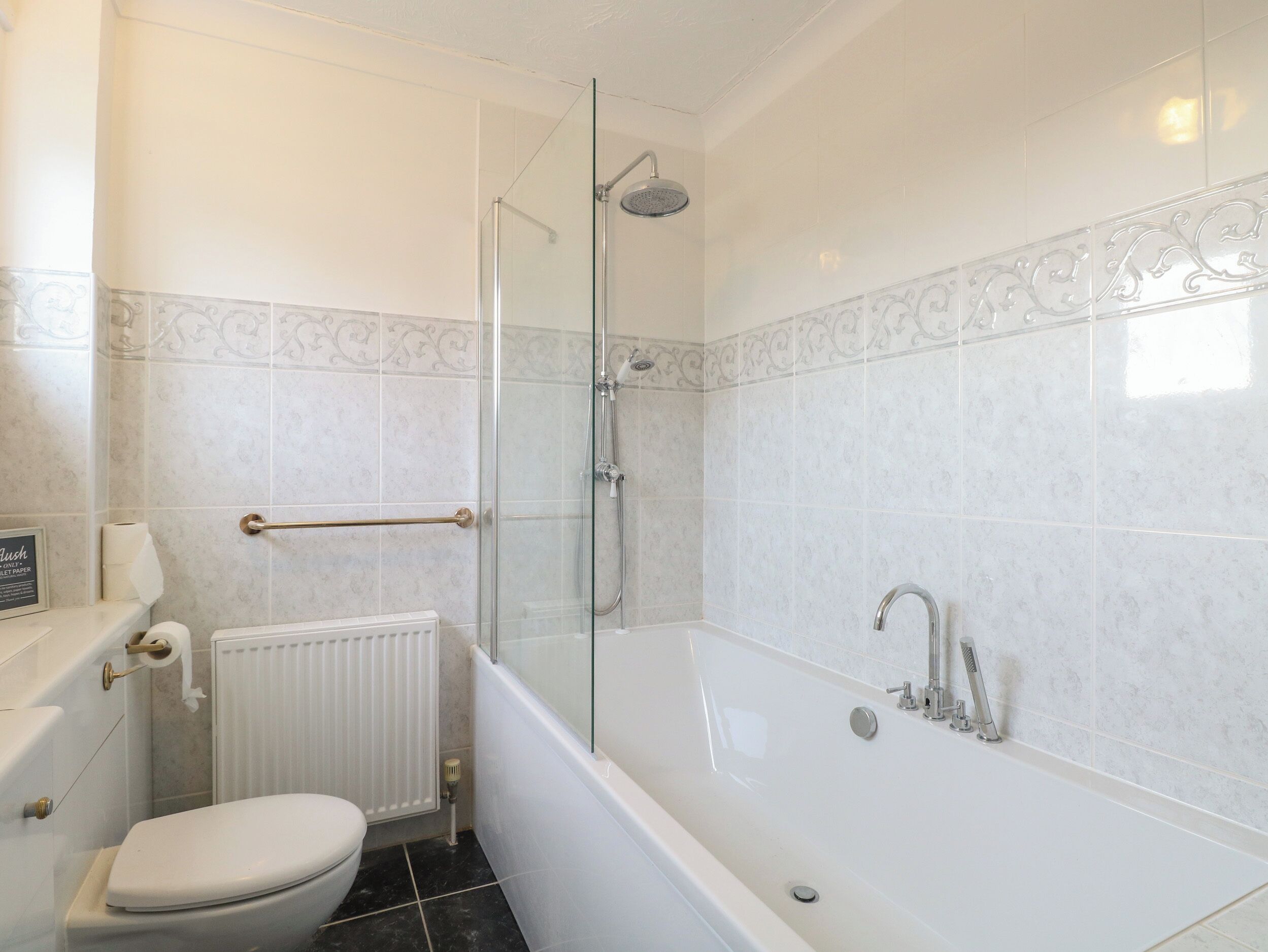 A bathroom with a toilet, a glass-enclosed shower, and a bathtub.