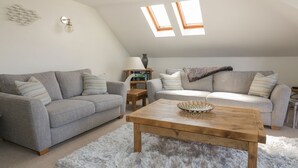 A loft-style living room with two grey sofas, a wooden coffee table, and a fluffy rug. - Atlantic View (Newquay)