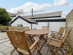 A patio with a round wooden table and six wooden chairs. - Crab Cottage (Delabole)