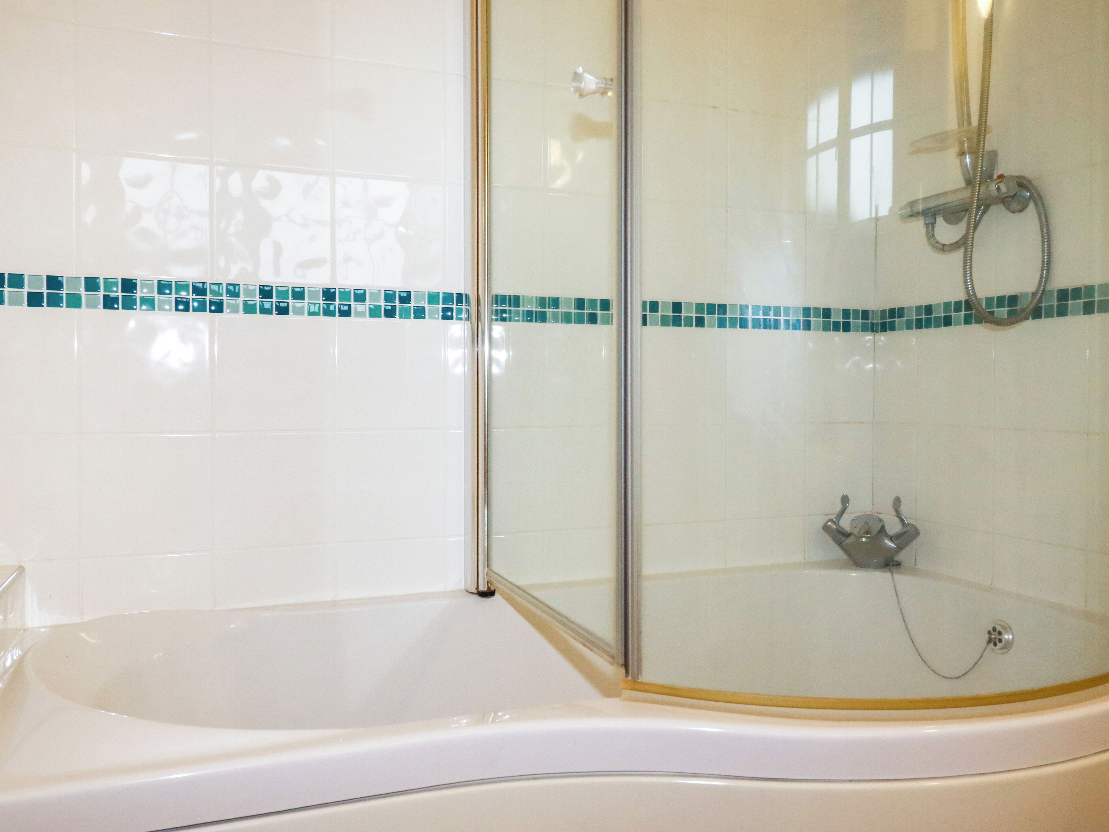 A modern bathroom with a glass-enclosed shower, a white bathtub, and a tiled floor.