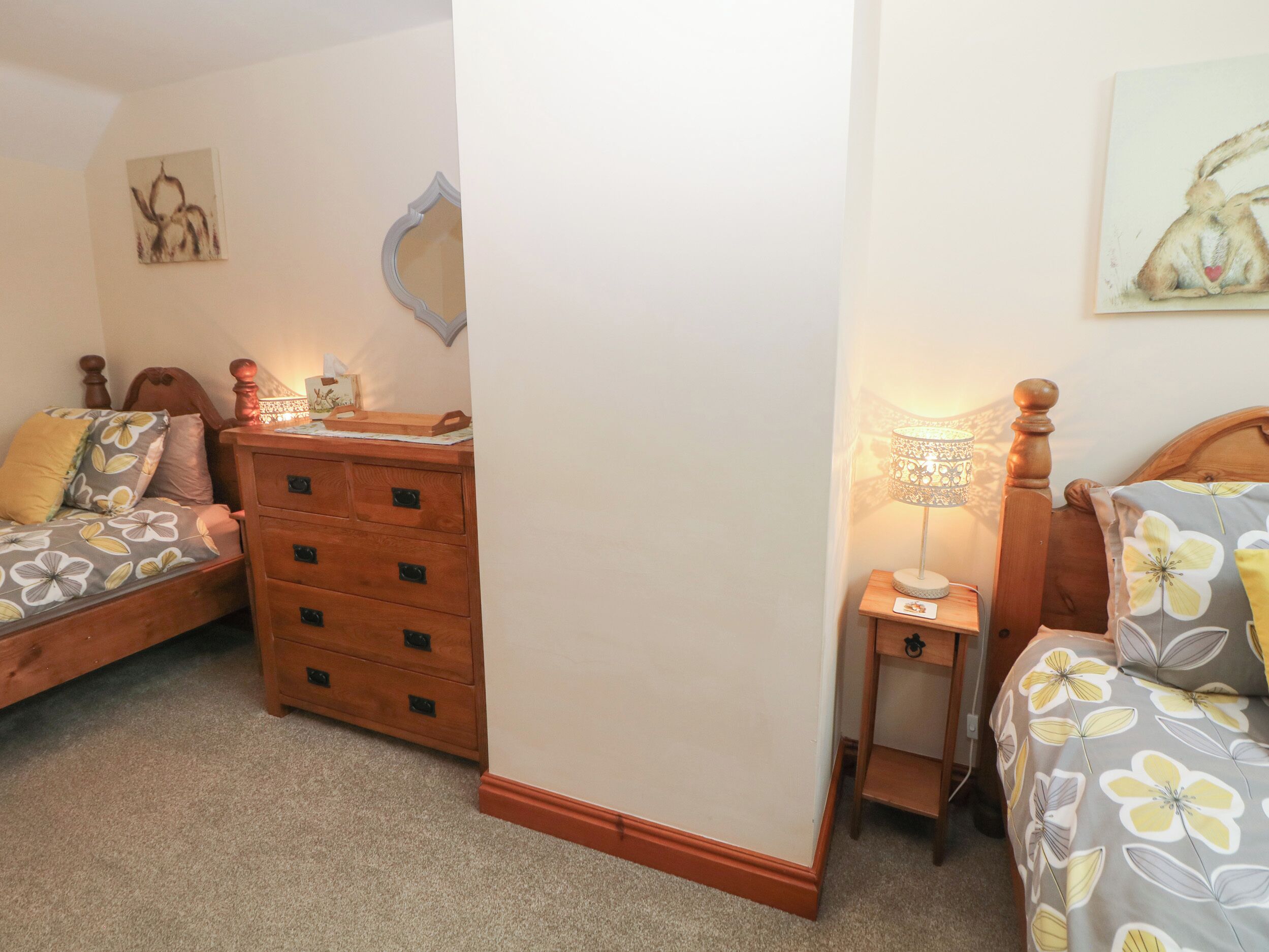 A bedroom with two beds, a dresser, a nightstand, and a wall-mounted mirror.