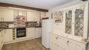 Una cucina con mobili bianchi, forno integrato, lavastoviglie e frigorifero.