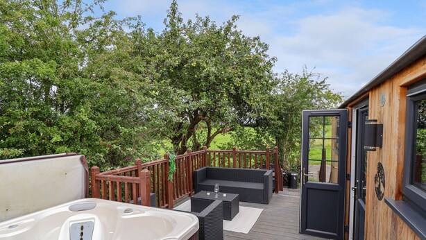 Un bain à remous, un espace salon extérieur et une terrasse en bois offrant une vue sur les arbres.