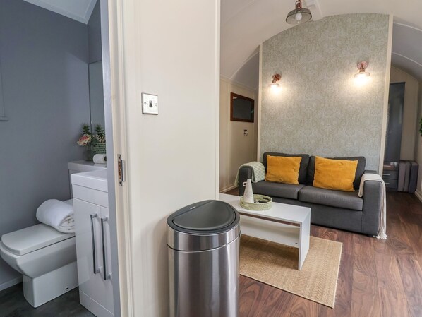 A modern living room with a grey sofa, a white coffee table, and a trash bin. - The Retreat (Wrexham)