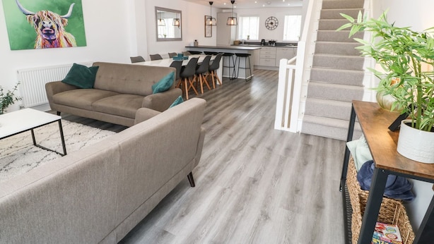 Un salon moderne comprenant un canapé, un coin repas, une cuisine et un escalier.