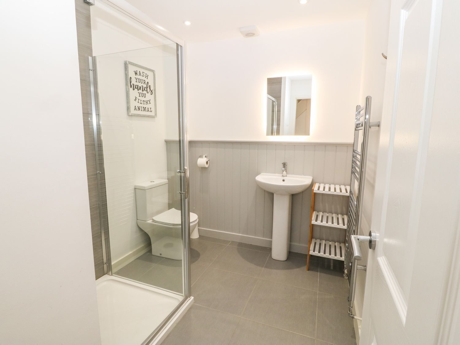 A modern bathroom with a glass shower enclosure, a toilet, a sink, and a towel rack.